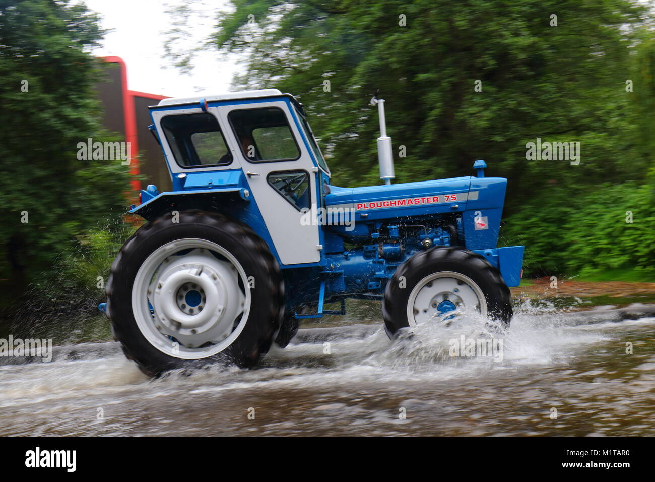 Ein Traktor fährt durch einen Fluss Ford in Ripon während einer jährlichen Traktor laufen von Newby Hall Stockfoto