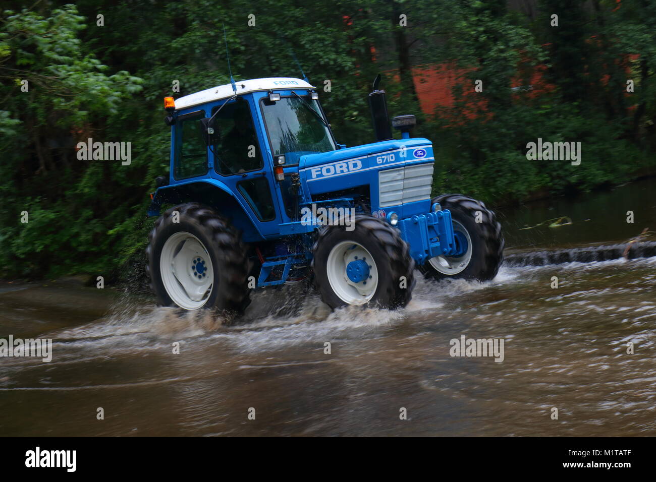 Ein Traktor fährt durch einen Fluss Ford in Ripon während einer jährlichen Traktor laufen von Newby Hall Stockfoto