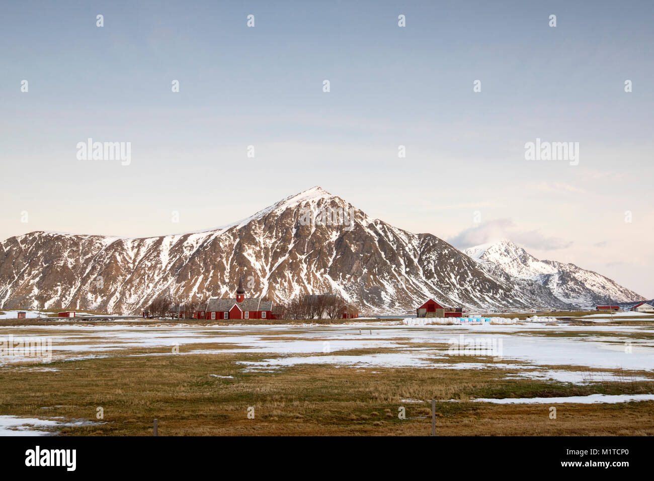 Die schneebedeckten Berge und eine Rote Kirche in Flakstad, flakstadøya Lofoten norwegen Stockfoto