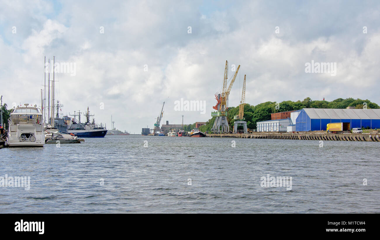 Hafen mit Kränen und industrielle Bauten auf auf der einen Seite und Freizeitaktivitäten segeln Boote auf der anderen Seite im Anschluss an die Ostsee von Liepaja, Latvi Stockfoto