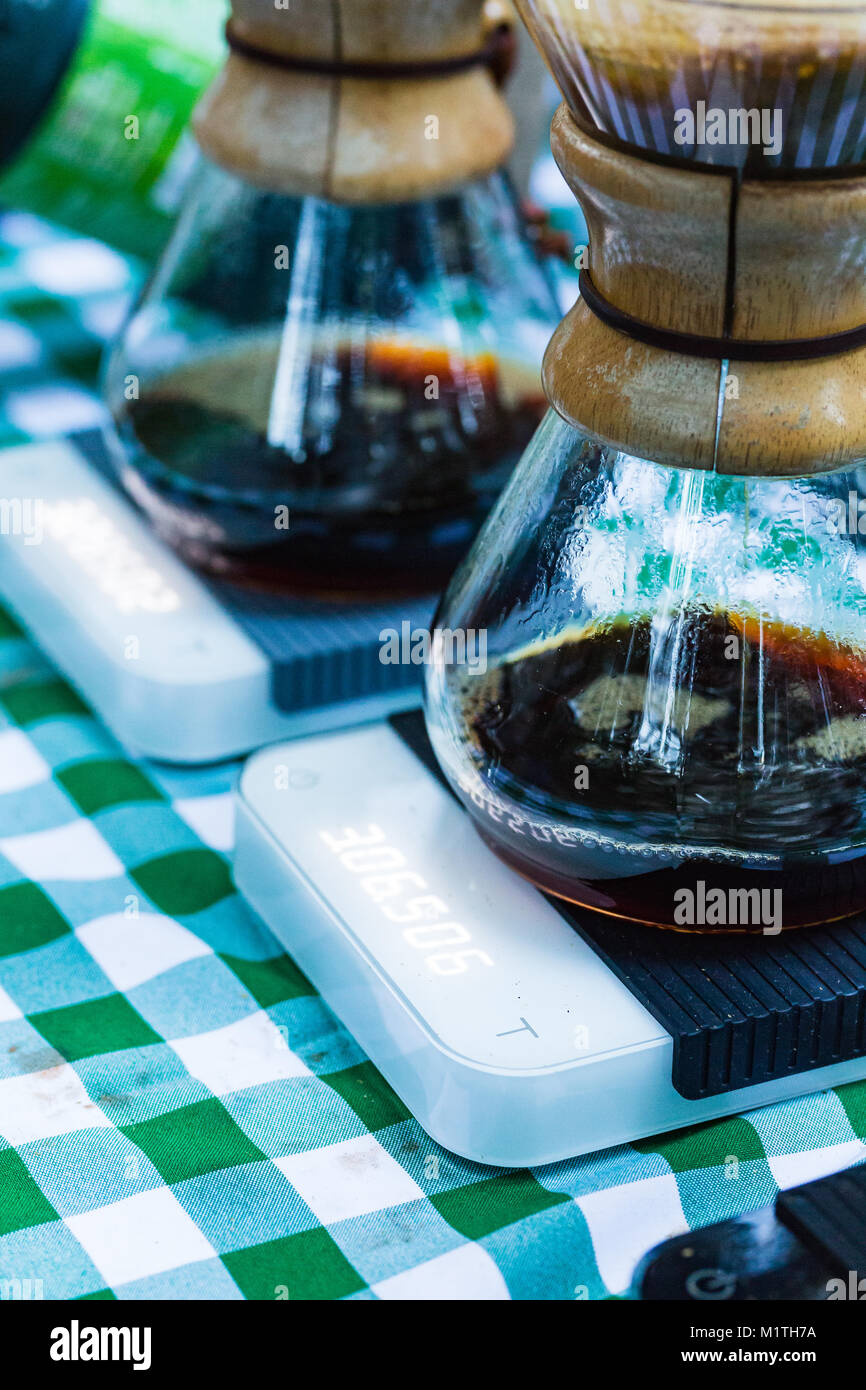 Über Kaffee tropft in artisan Glas Brauer sitzen auf elektronische Waagen Gießen, während draußen auf einem Picknicktisch Stockfoto