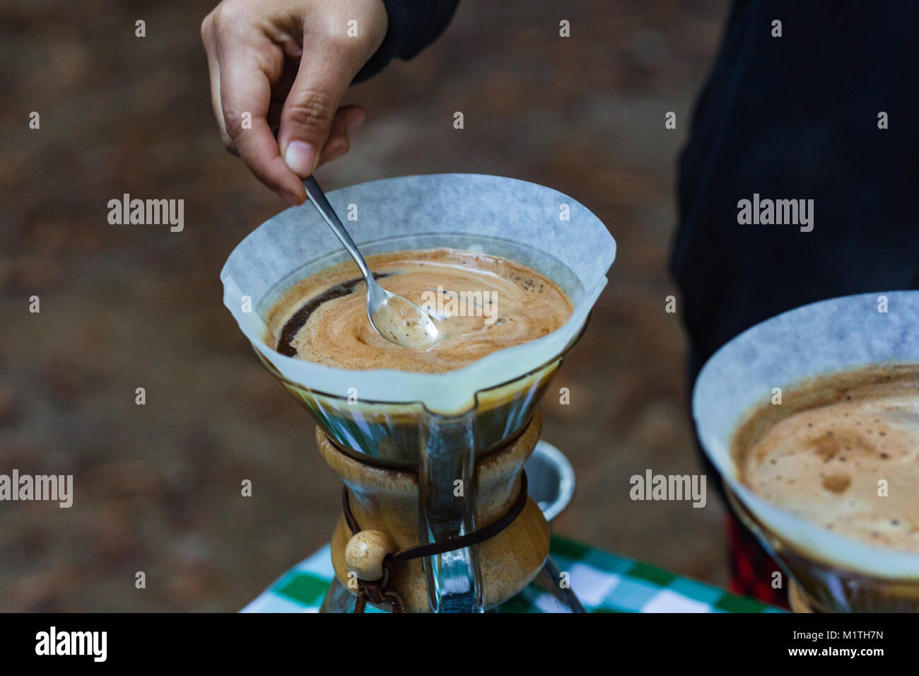 Barista rührt über Kaffee in artisan Glas Brauerei gießen, während draußen Stockfoto