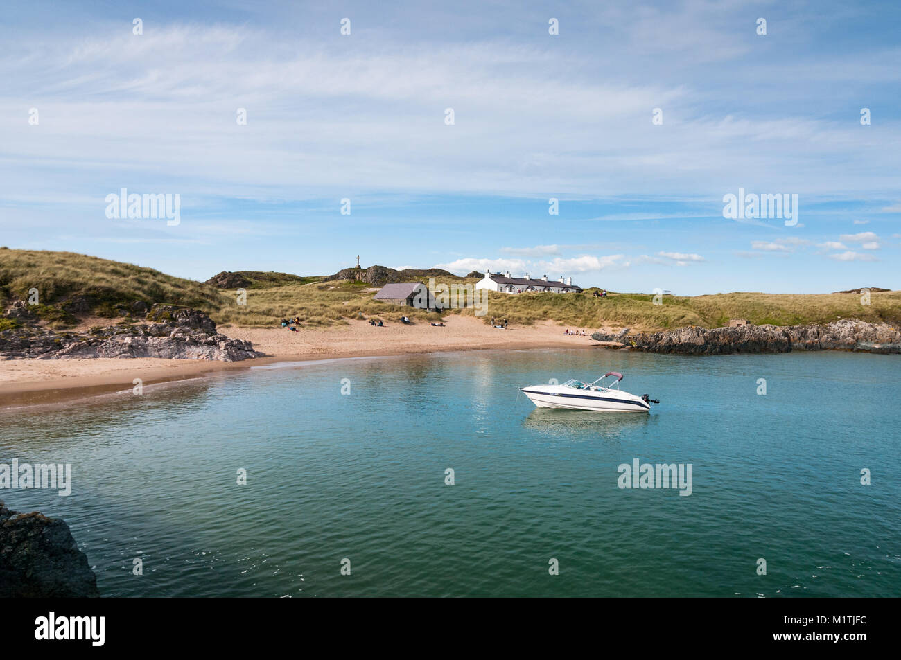 Llanddwyn Island Beach und Bucht mit Menschen am Strand und cottages Pilots im Hintergrund auf einem sonnigen späten Tag Sommer, Anglesey, Wales Stockfoto