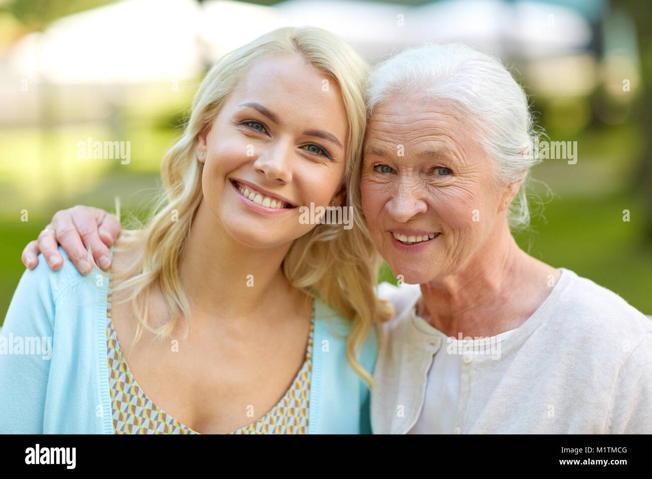 Tochter mit älteren Mutter umarmt auf Parkbank Stockfoto