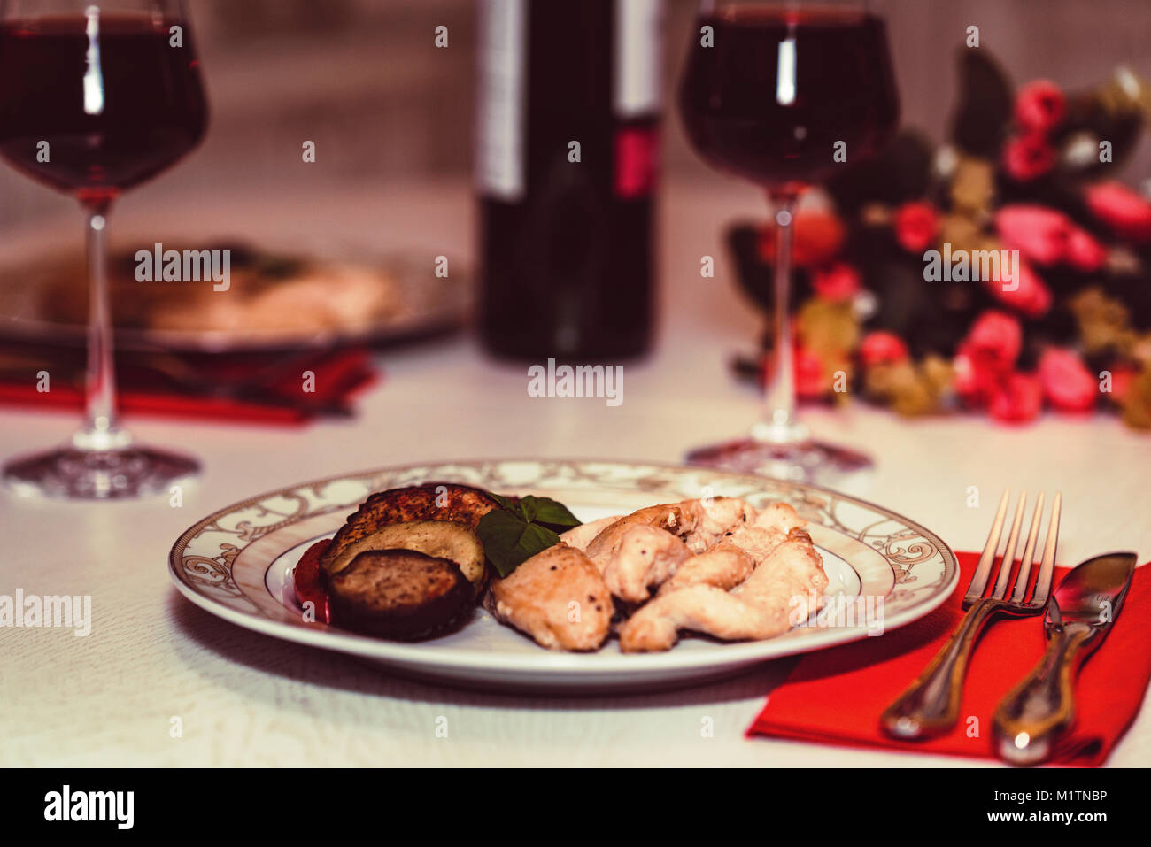 Romantisches Abendessen für Zwei mit Wein, Fleisch und Blumen Stockfoto