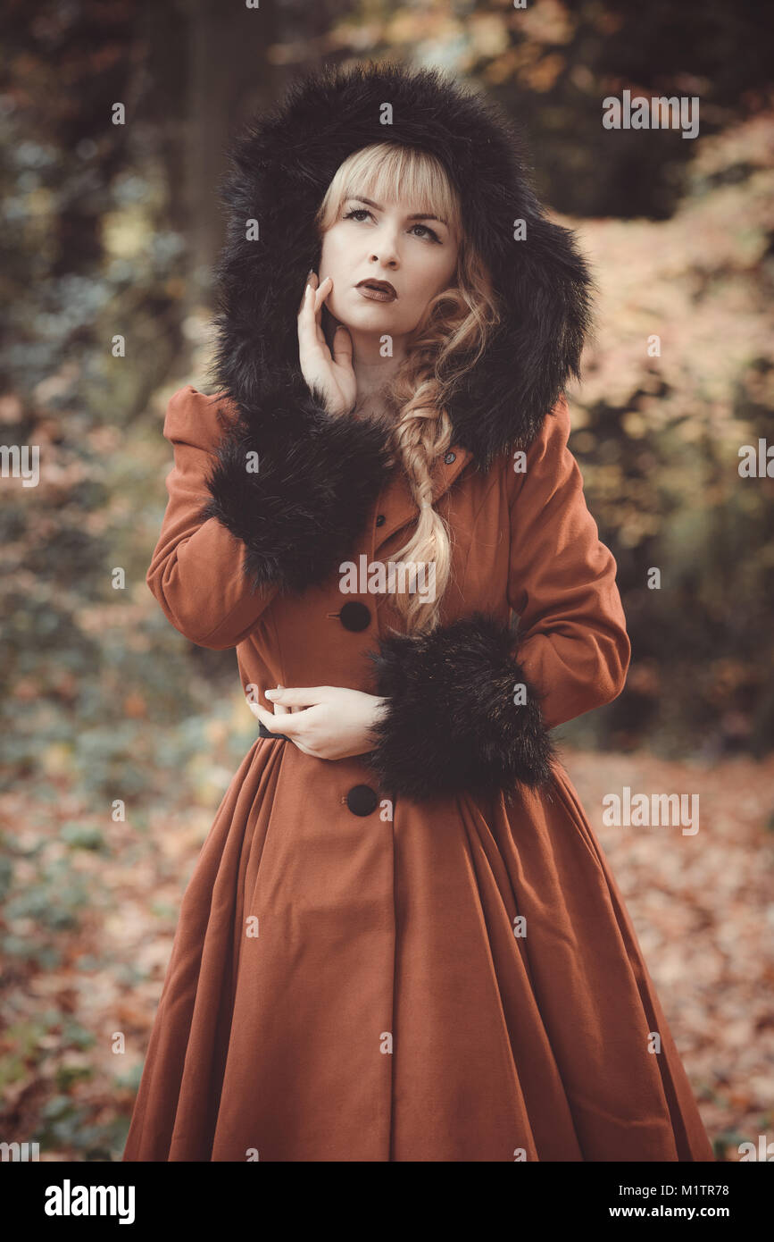 Frau in Vintage roten Mantel mit Fell Kapuze im Herbst Wald Stockfoto