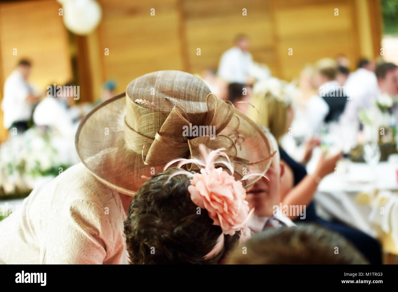 Mutter der Braut trägt einen großen Hut Gespräche zu einer Hochzeit Gast in privaten an einer Hochzeit in der Familie Stockfoto