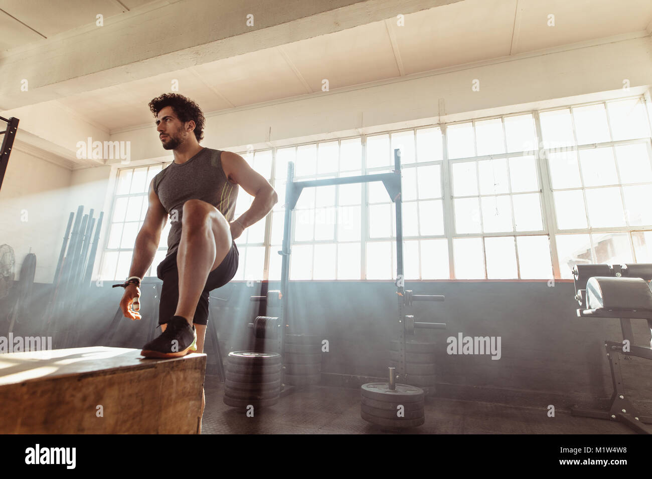 Muskulöse männlichen Athleten stehen, Springen an Cross Training Gym. Passen junge Mann, der mit einem Feld im Health Club. Stockfoto