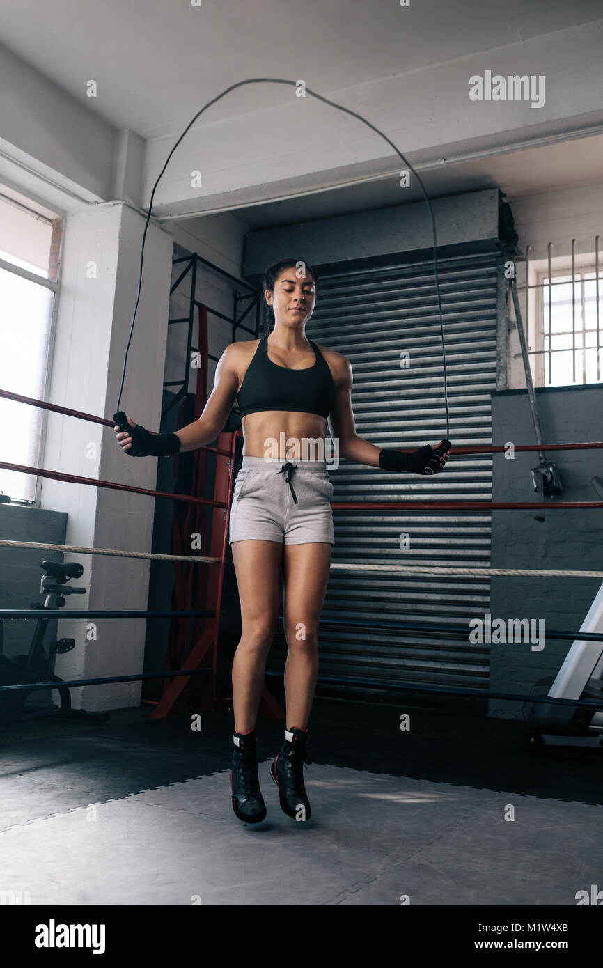 Weibliche Boxer in der Aufwärmphase in einem Boxring. Frau Training mit einem Springseil. Stockfoto