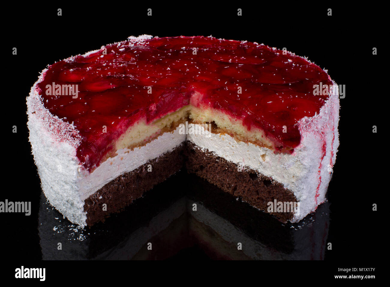 Stück einen großen Kuchen in Kokos Späne mit Erdbeeren in Gelee auf schwarzem Hintergrund Stockfoto