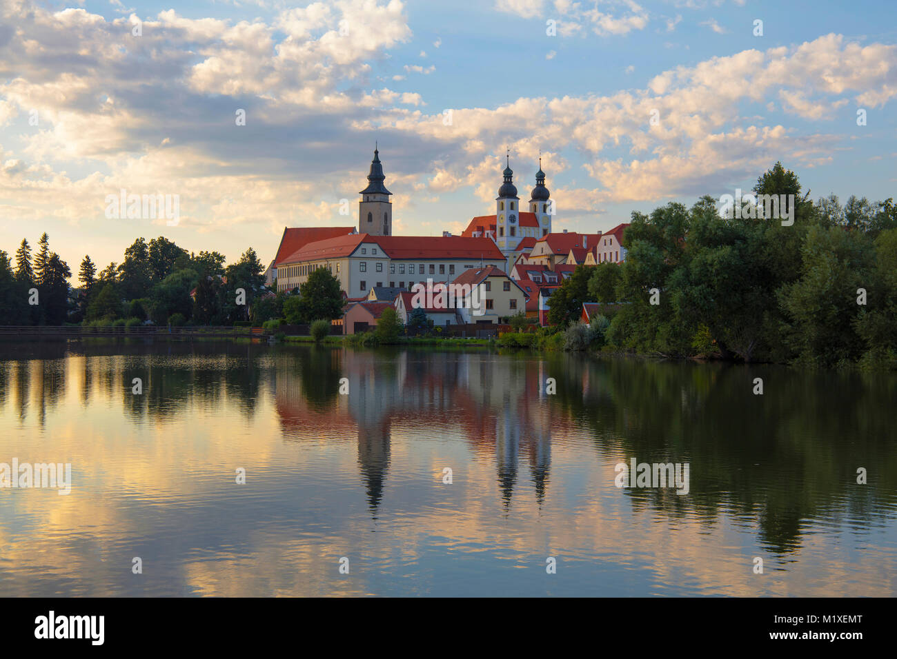 Unsere Liebe Frau Kloster (die Abtei von Nova Aufstieg) mit Reflexion über das ruhige Wasser des Sees und bewölkter Sonnenuntergang Himmel in Telc, Mähren, Tschechien Stockfoto