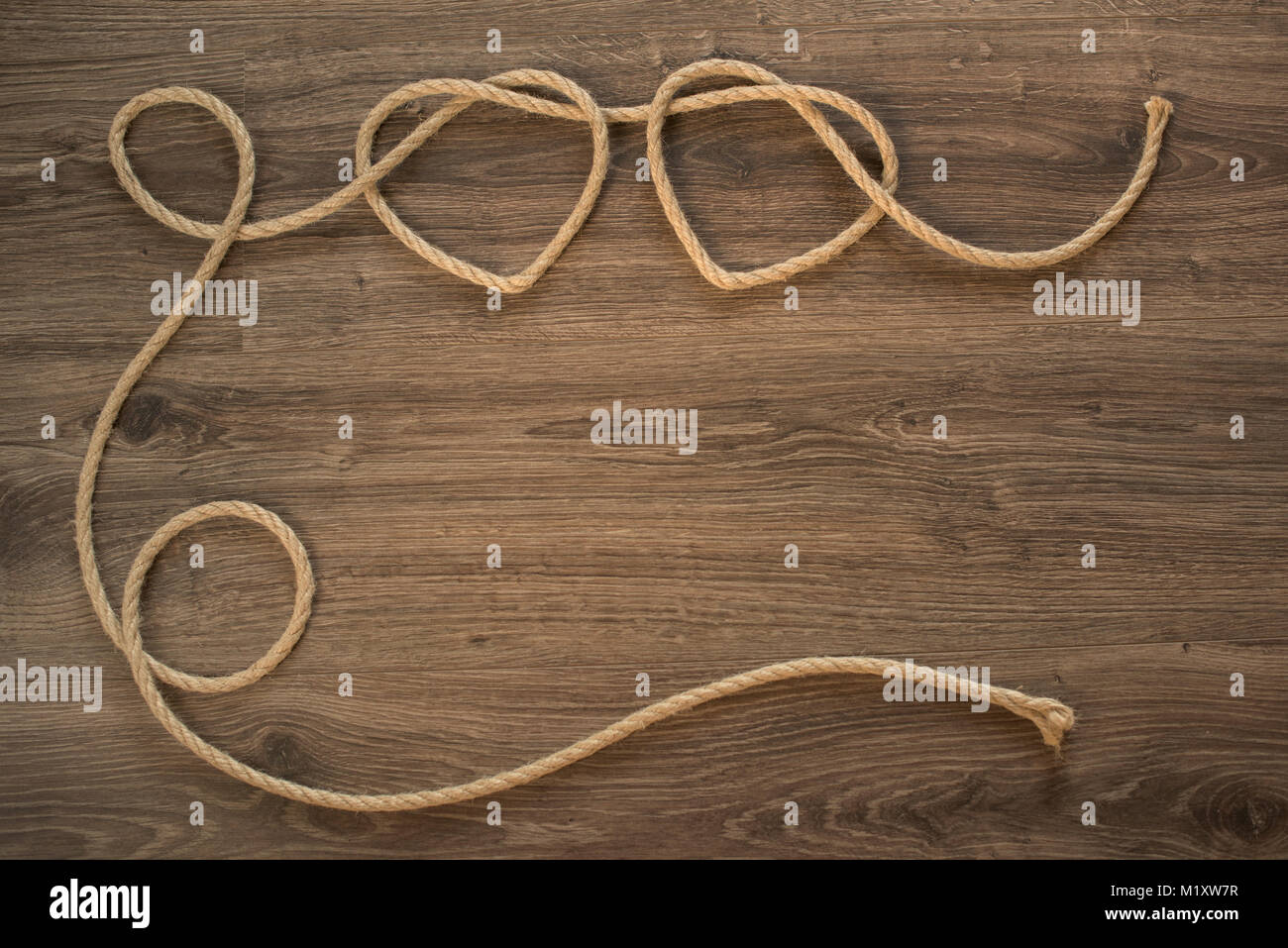 Zwei Herzen Formen aus Seil Knoten auf der Holzplatte Stockfoto