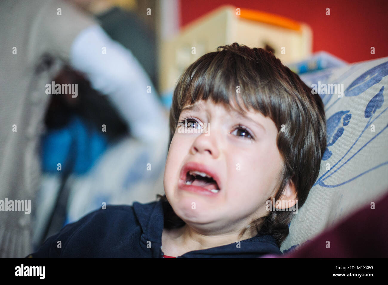 6 Jahre alter Junge traurig und weinend in seinem Haus sitzen auf der Couch Stockfoto