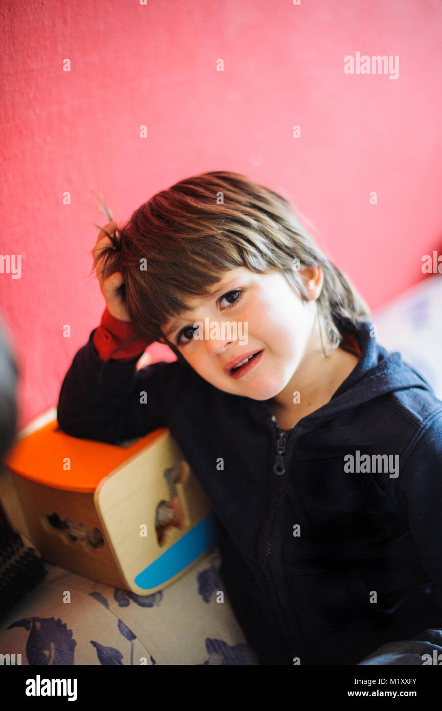 6 Jahre alter Junge traurig und weinend in seinem Haus sitzen auf der Couch Stockfoto