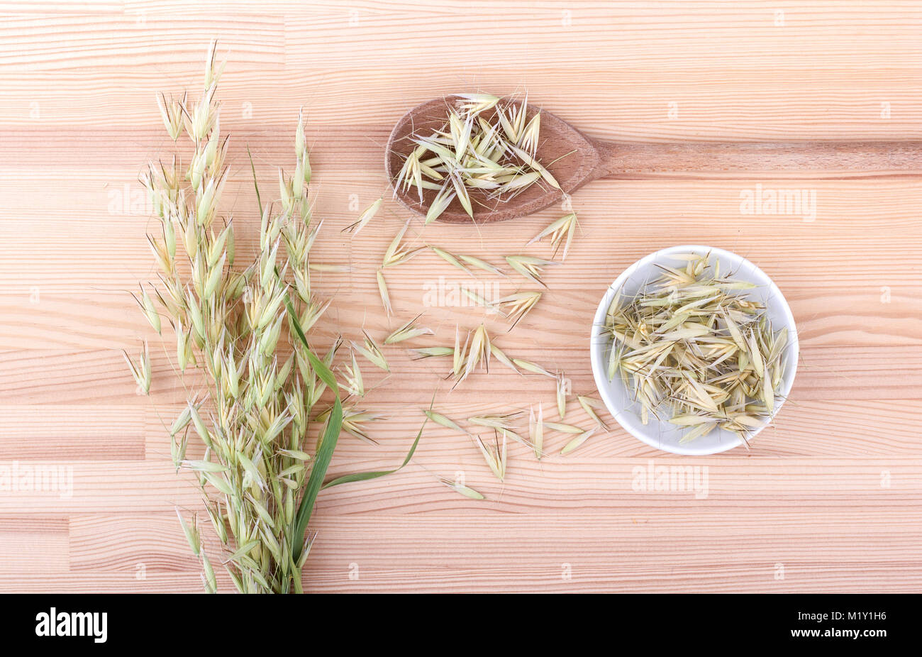 Blick von oben auf einen hölzernen Löffel und eine Porzellanschale mit getrockneten Oat Stockfoto