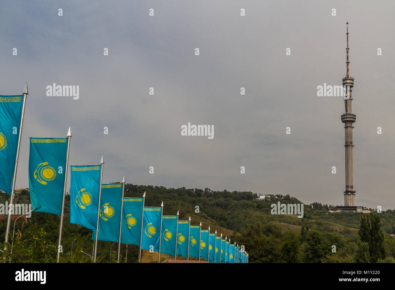 Linie der blauen und gelben Kasachische Fahnen im Wind, mit Kok-Tobe Fernsehturm im Hintergrund Almaty, Kasachstan, Asien. Stockfoto