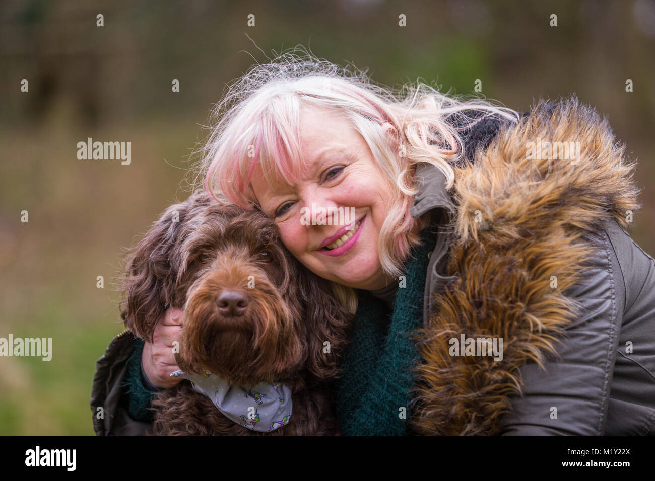 Frau mittleren Alters mit ihrem Hund draußen im Park lächelnd Stockfoto