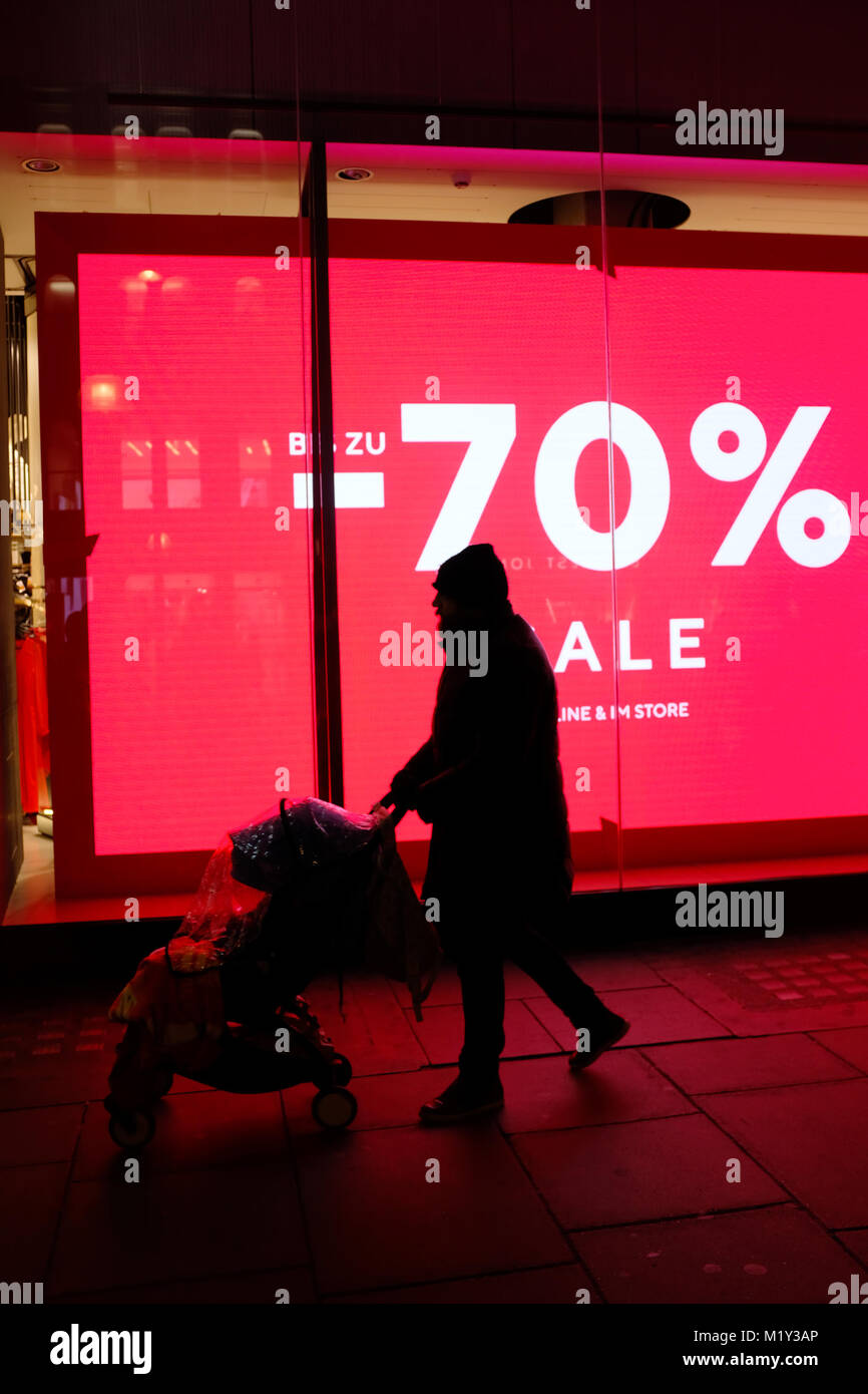 Silhouette der Elternteil, Kind im Kinderwagen vor hinterleuchtete rote Verkauf Zeichen auf der Oxford Street, London, England, Großbritannien Stockfoto