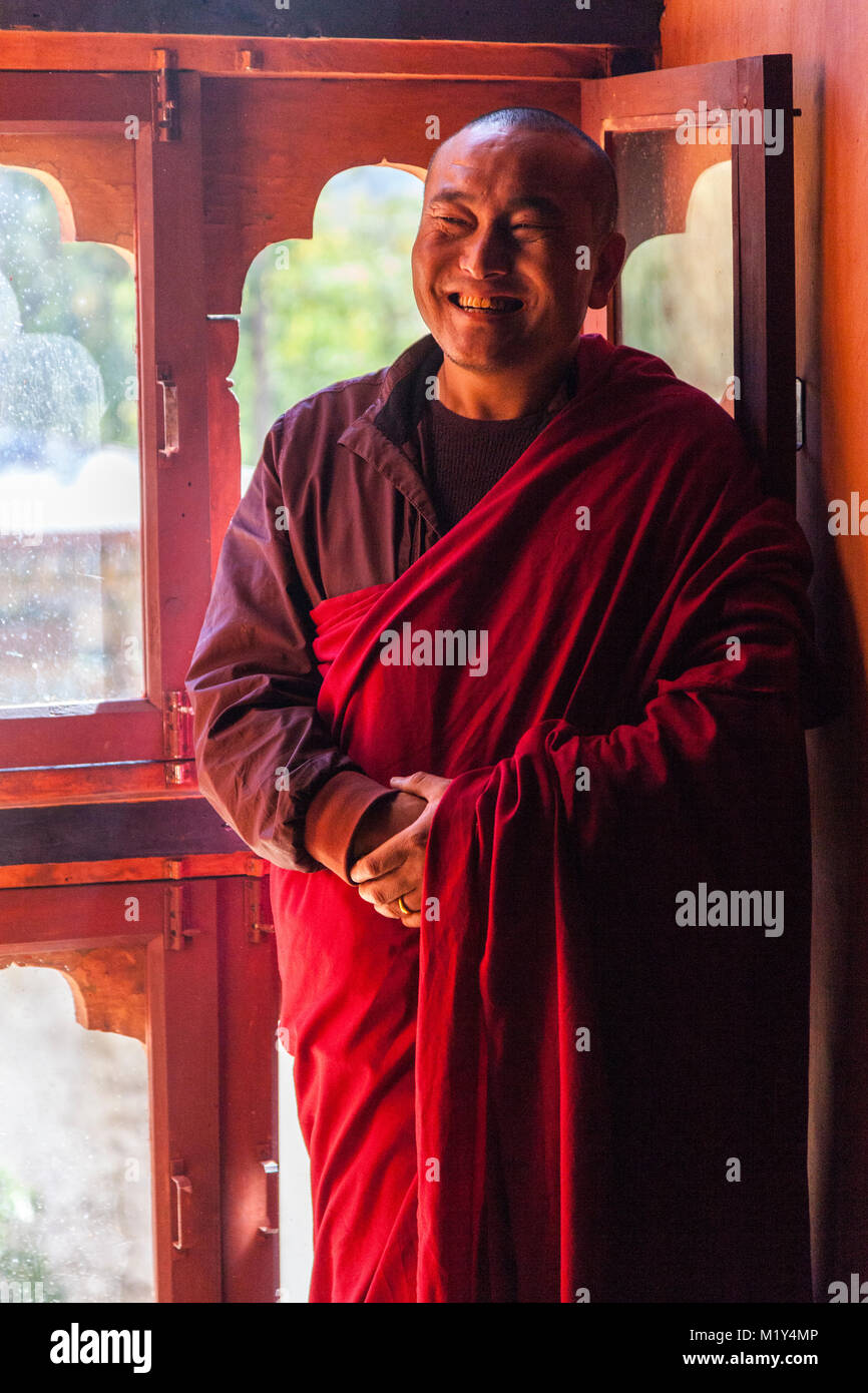 Paro, Bhutan. Buddhistischer Mönch lächelnd durch die Fenster seines Tempels. Stockfoto