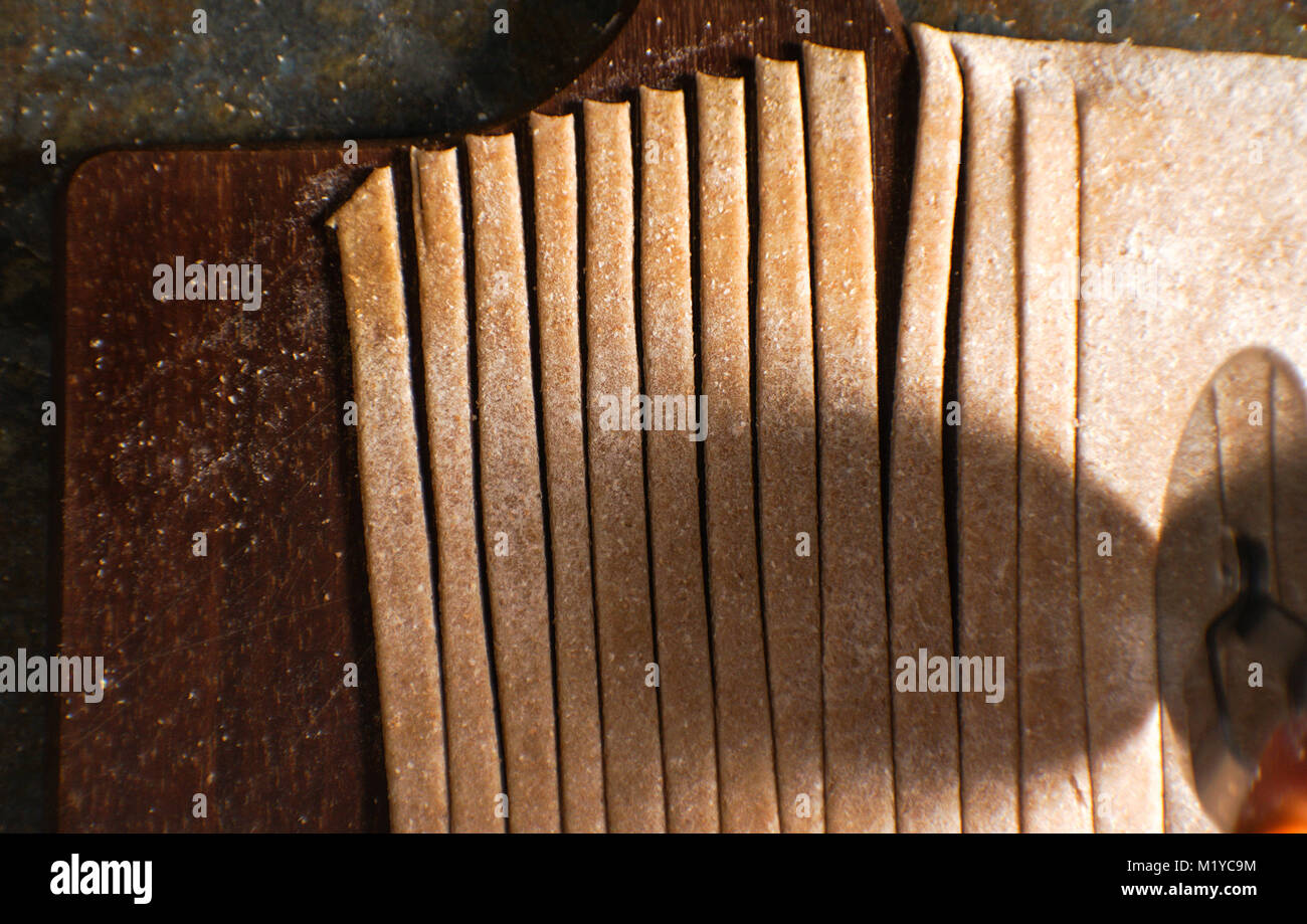 Schneiden Sie den Teig für Teigwaren auf glatte Streifen horizontal Stockfoto