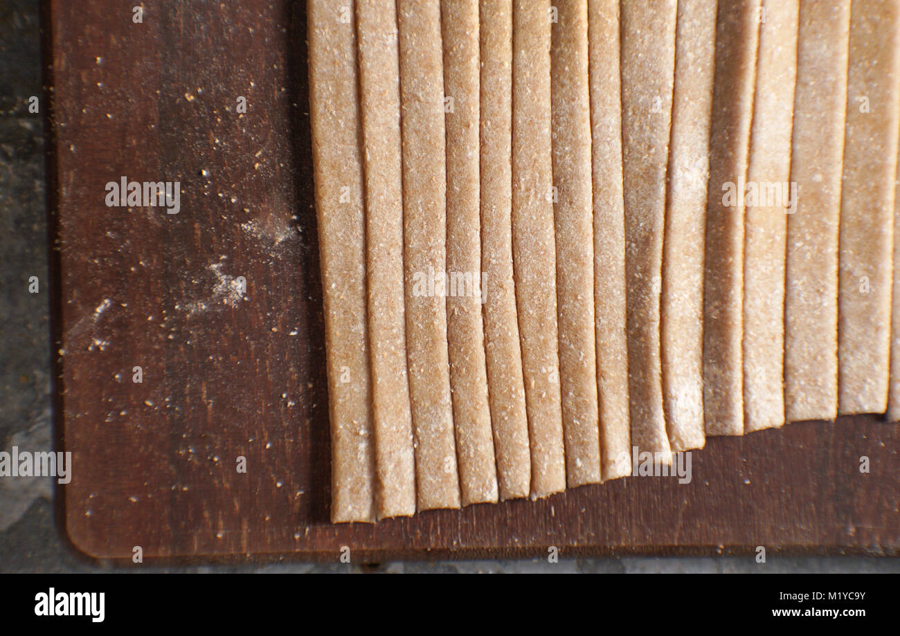 Pasta aus Vollkornmehl auf einem Holzbrett Ansicht von oben horizontal Stockfoto
