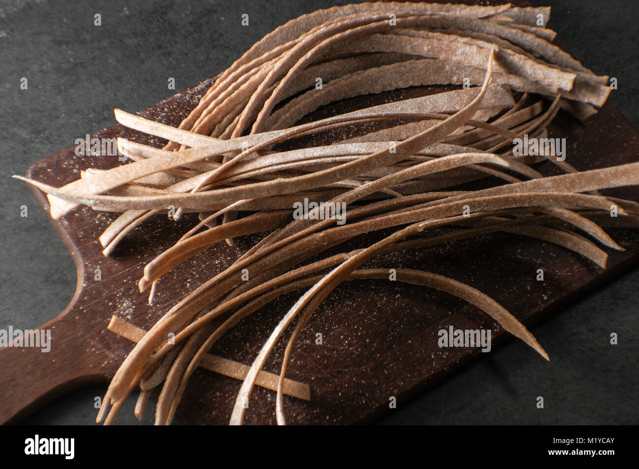 Trockene Paste aus Vollkornmehl auf einem Holzbrett diagonal Horizontale Stockfoto