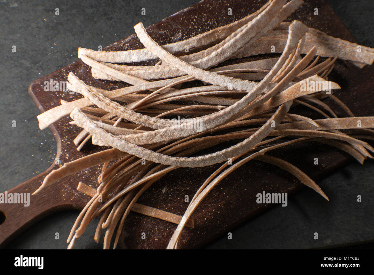 Trockene Paste aus Vollkornmehl auf einem Holzbrett closeup horizontal Stockfoto