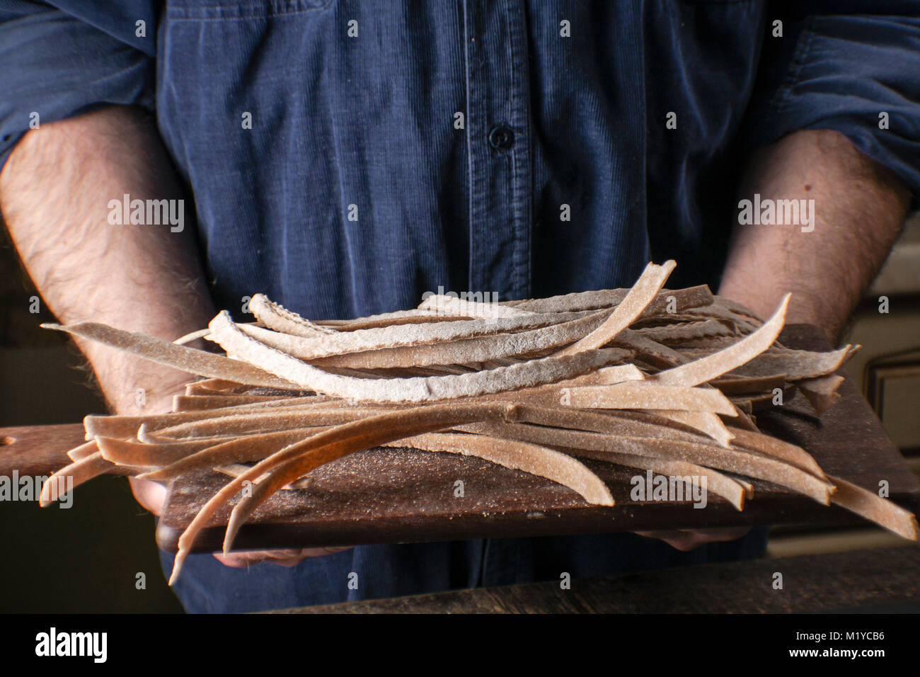 Mann hält eine Holzplatte mit einer Paste in seinen Händen horizontal Stockfoto