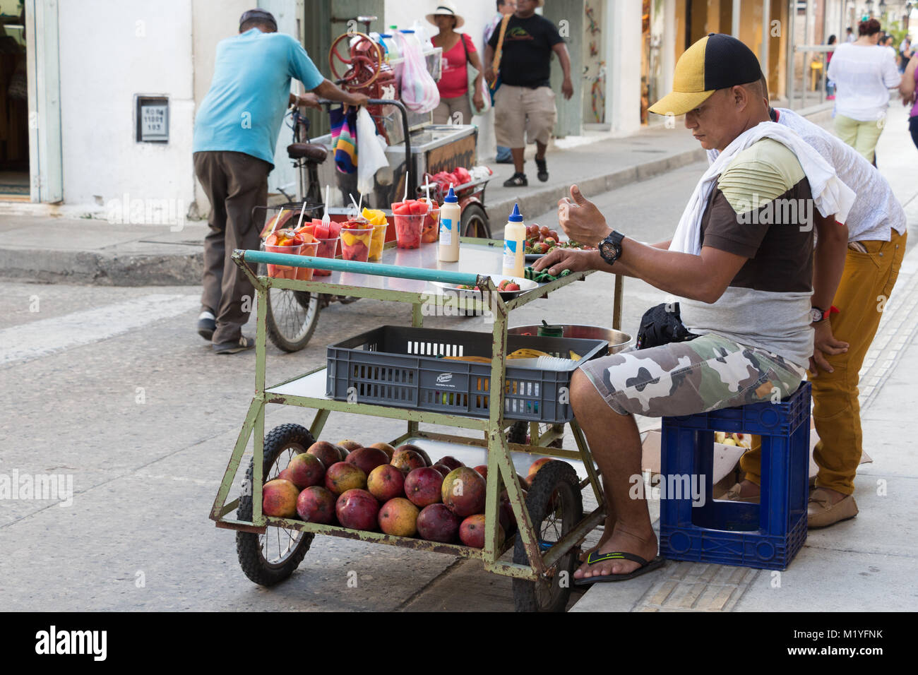 Cartagena, Kolumbien - Januar 23th, 2018: eine Frucht street Hersteller auf seinem mobilen saß auf seinem Metall Warenkorb mit Früchten in der Altstadt von Cartagena, Stockfoto