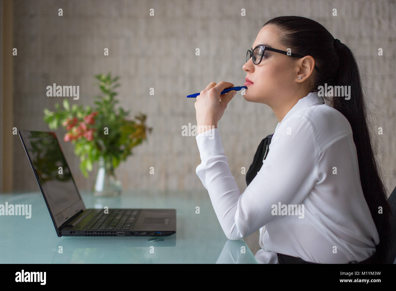 Frau denken über Geschäftsmöglichkeiten in office at laptop Stockfoto