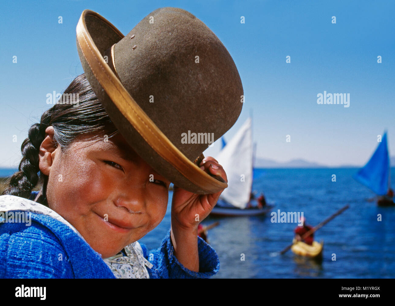 Bolivien. Copacabana. Titicaca See. Anden. Aymara indisches Mädchen mit typischer Kühner hat vor schilfboote. Stockfoto