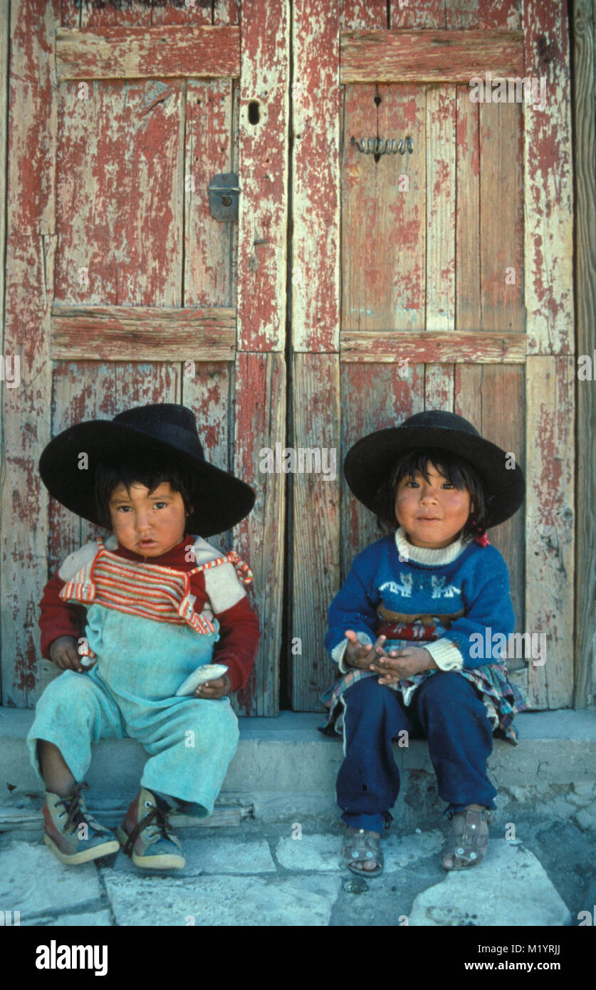 Bolivien. In der Nähe von Uyuni. Anden. Aymara indische Mädchen und Jungen mit typischen Bowler Hut vor der Tür. Stockfoto