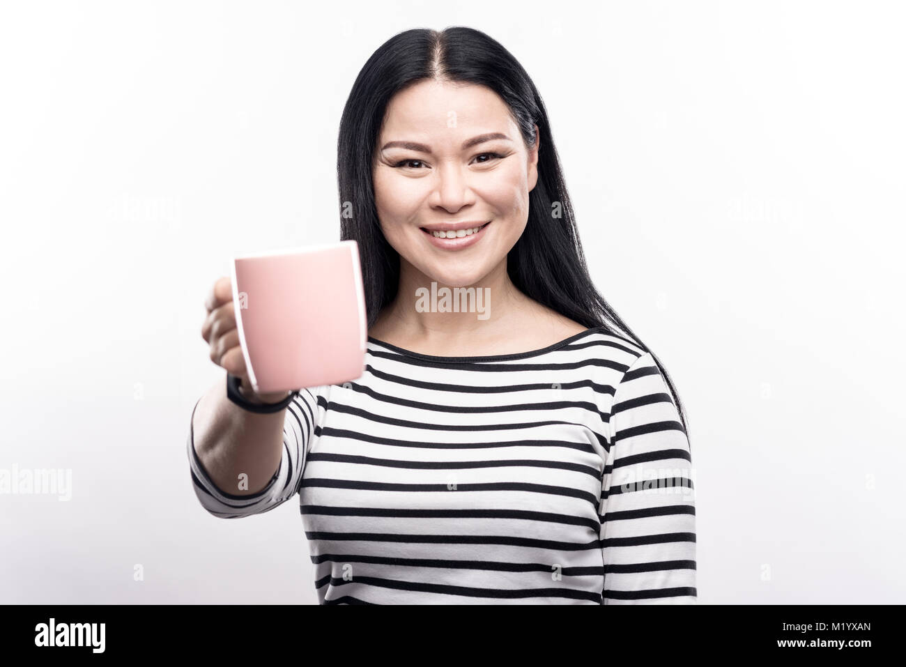 Fröhliche dunkelhaarige Frau übergabe Coffee Mug Stockfoto