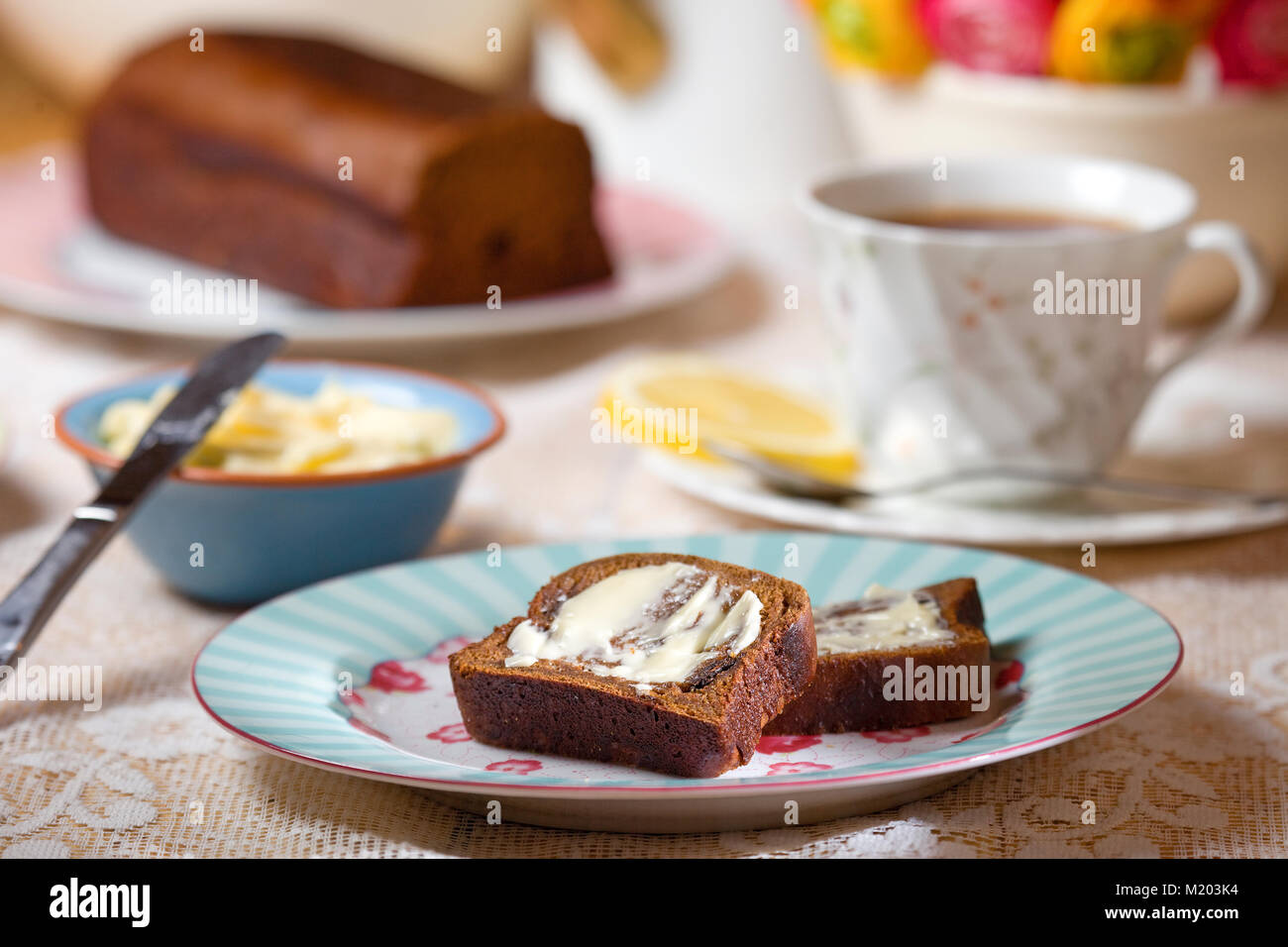Tabelle Einstellung mit in Scheiben geschnittenen Malz Brot mit Butter und schwarzer Tee mit Zitrone Stockfoto