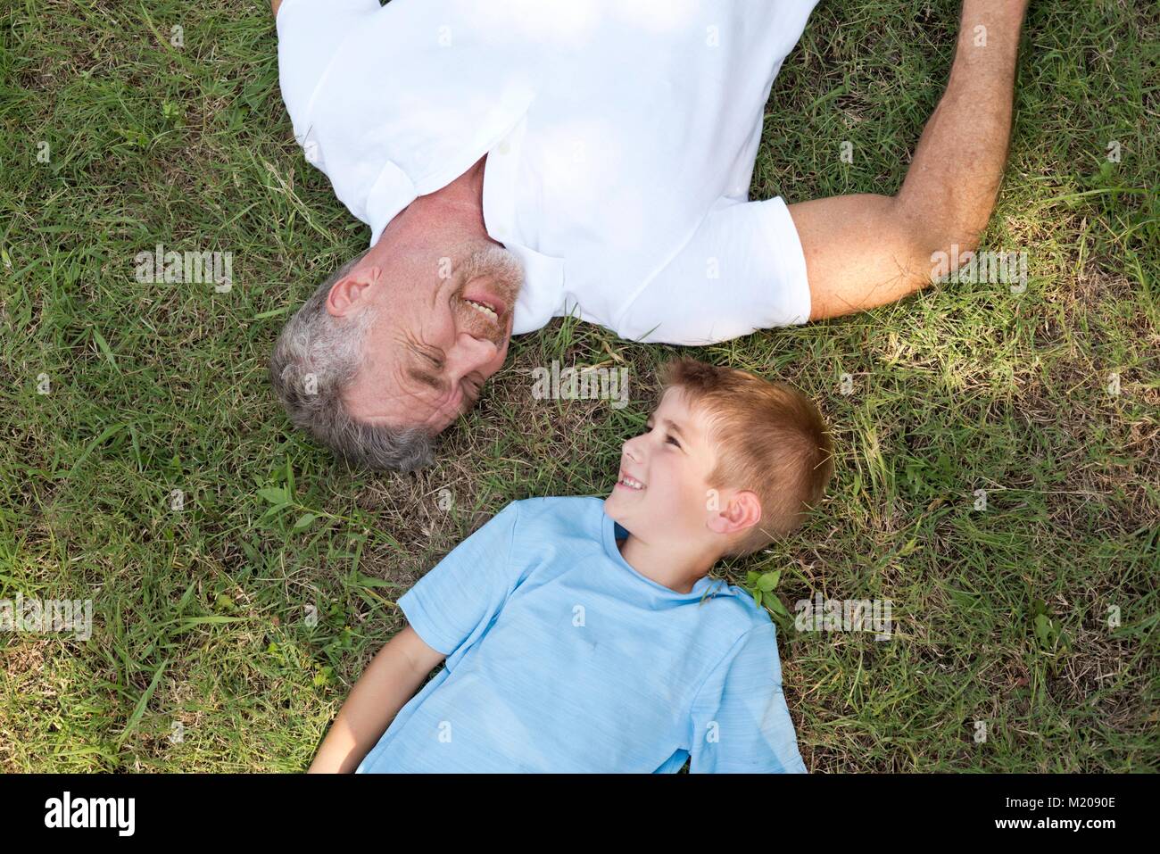 Großvater und Enkel liegen auf Gras, hohen Winkel. Stockfoto