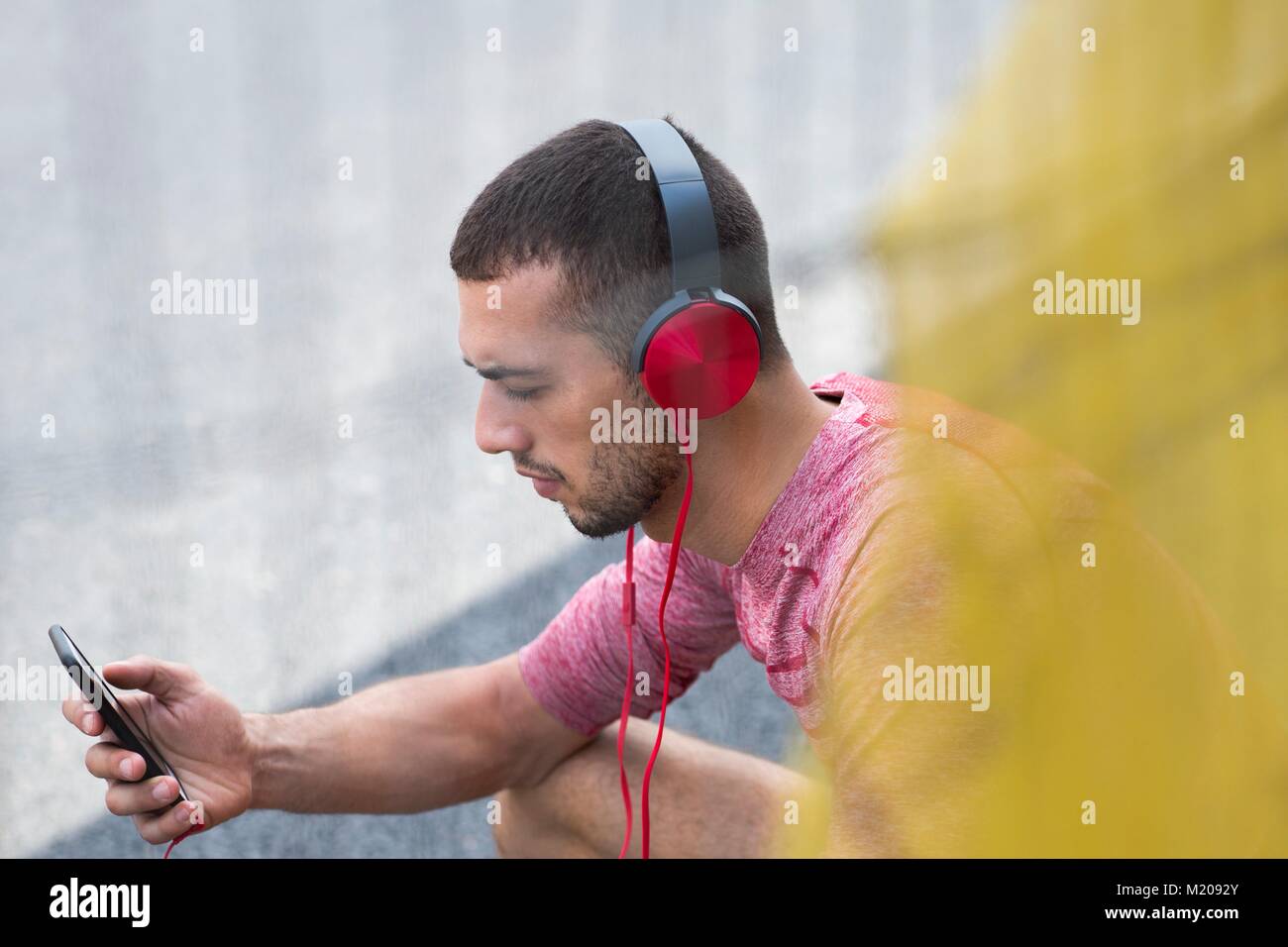 Junger Mann mit Kopfhörern hören von Musik auf dem Smartphone. Stockfoto