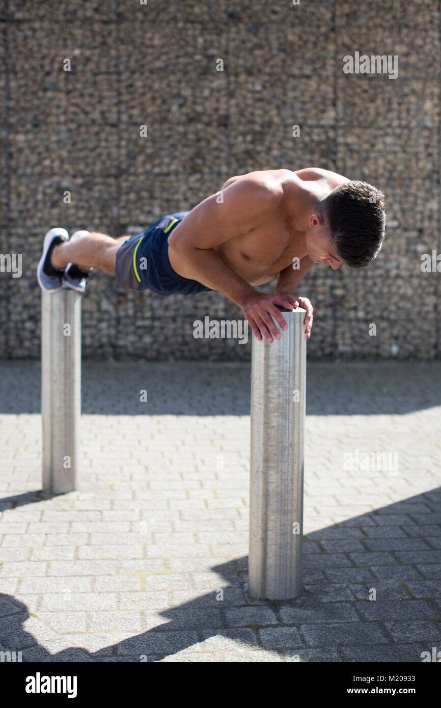 Junger Mann auf zwei Poller, Push-up. Stockfoto