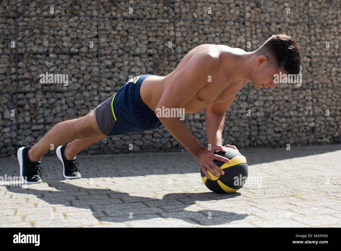 Junger Mann Balancieren auf Medizinball, Push-up. Stockfoto