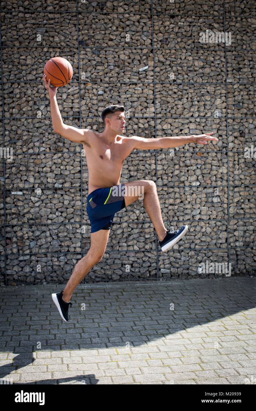 Junger Mann springen mit Basketball. Stockfoto