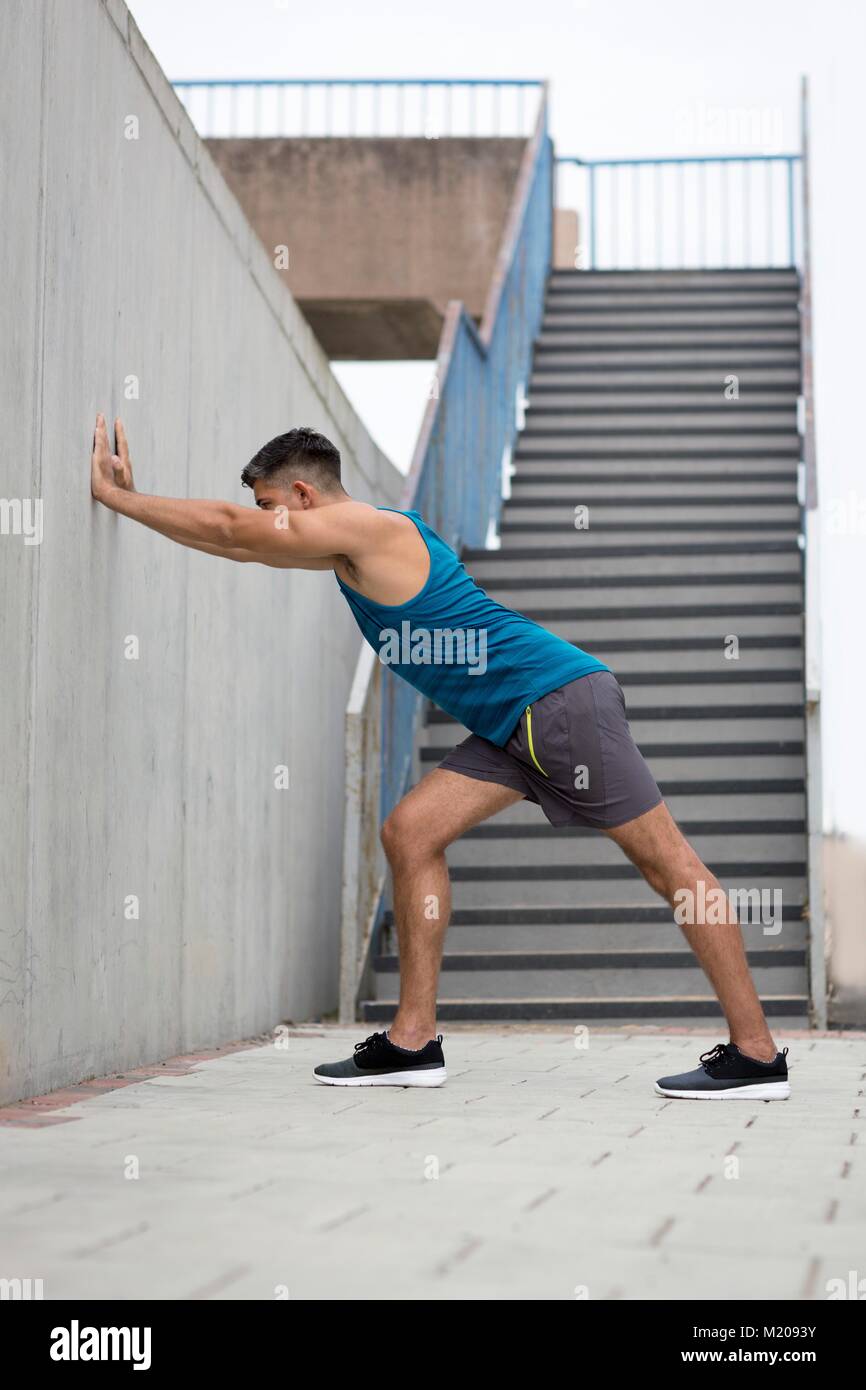 Junger Mann stretching Bein gegen die Wand. Stockfoto