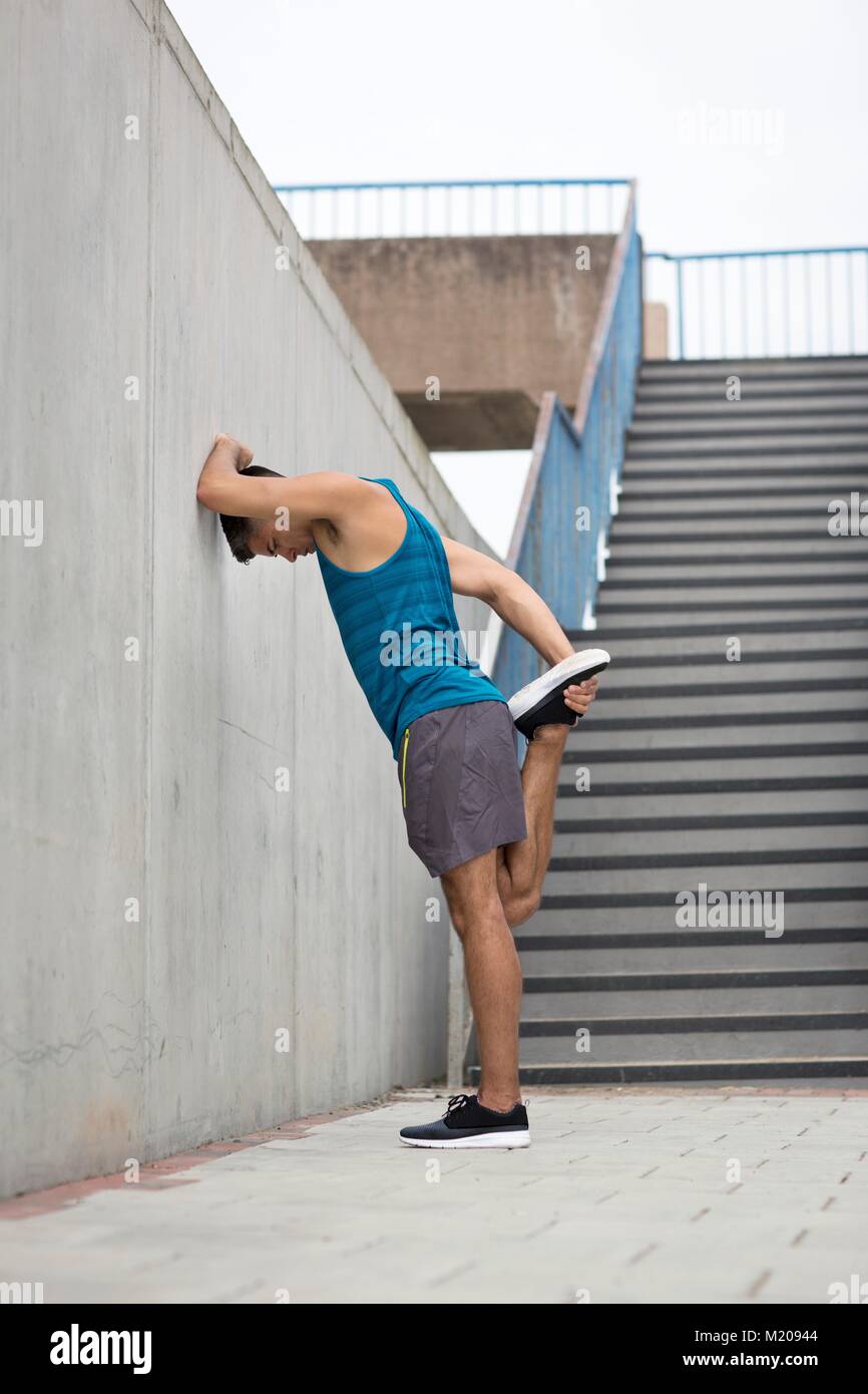 Junger Mann stretching Bein durch die Wand. Stockfoto