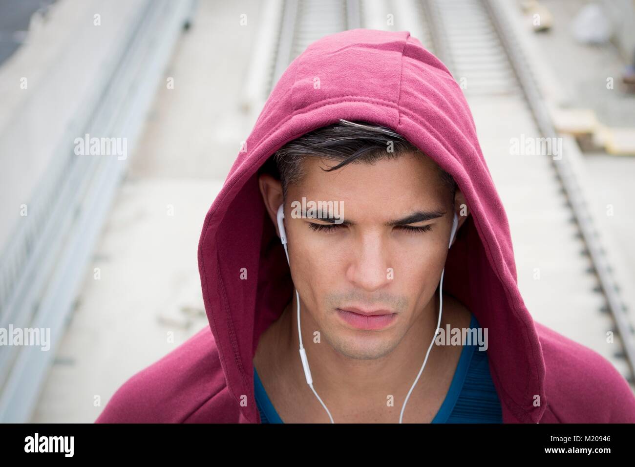 Junger Mann mit Ohrhörer und Kapuzen Top. Stockfoto