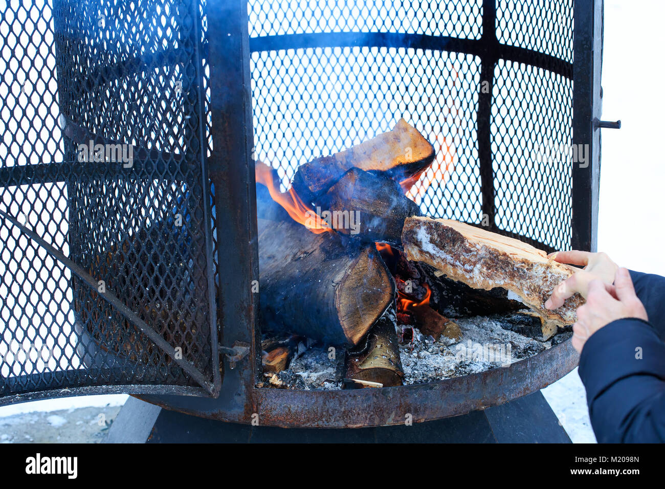 Outdoor metallic Kamin im Winter mit Brennholz in den Brennvorgang. Holz - brennende Feuergrube mit abnehmbaren Feuer pan. Stockfoto