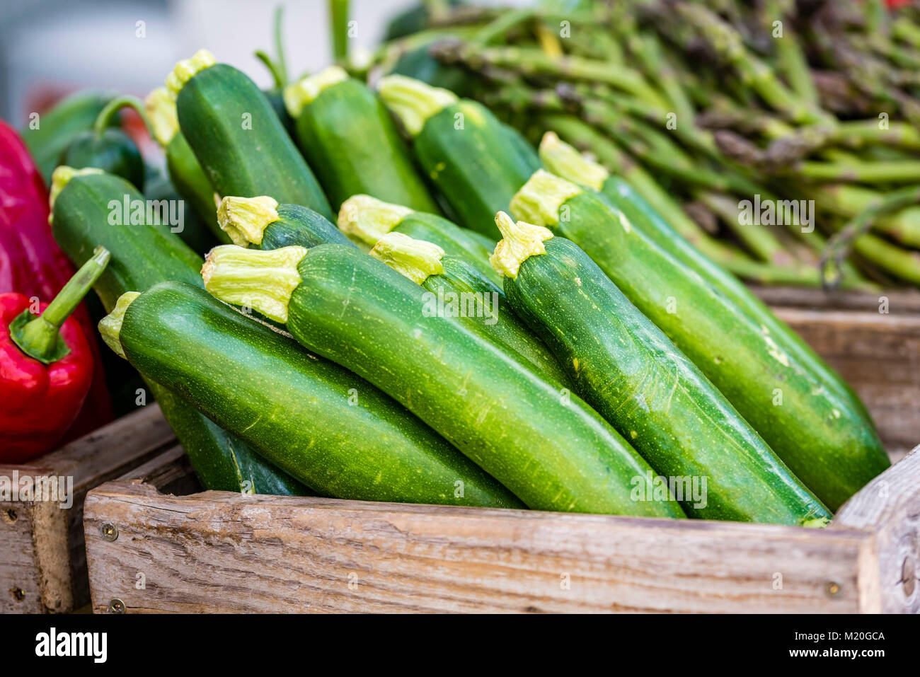 Organische frische Gemüse in Kisten aus Holz, am Markt angezeigt, Nahaufnahme. Spargel, Zucchini, rote Paprika am Marktstand, Sydney, Australien. Stockfoto