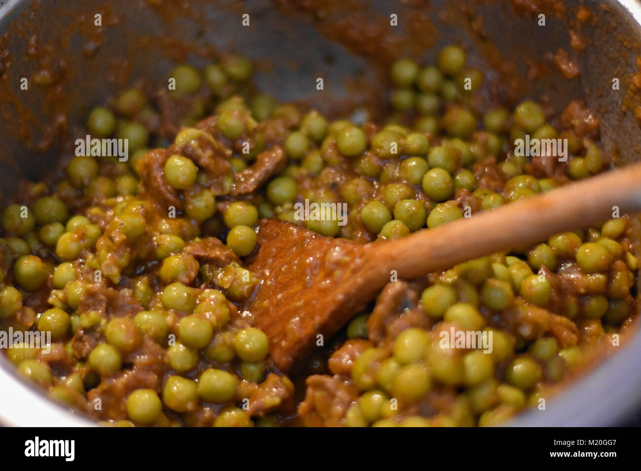Kochen grüne Erbsen in Soße, whit Holzlöffel/closeup rühren noch Life Food Fotografie Stockfoto