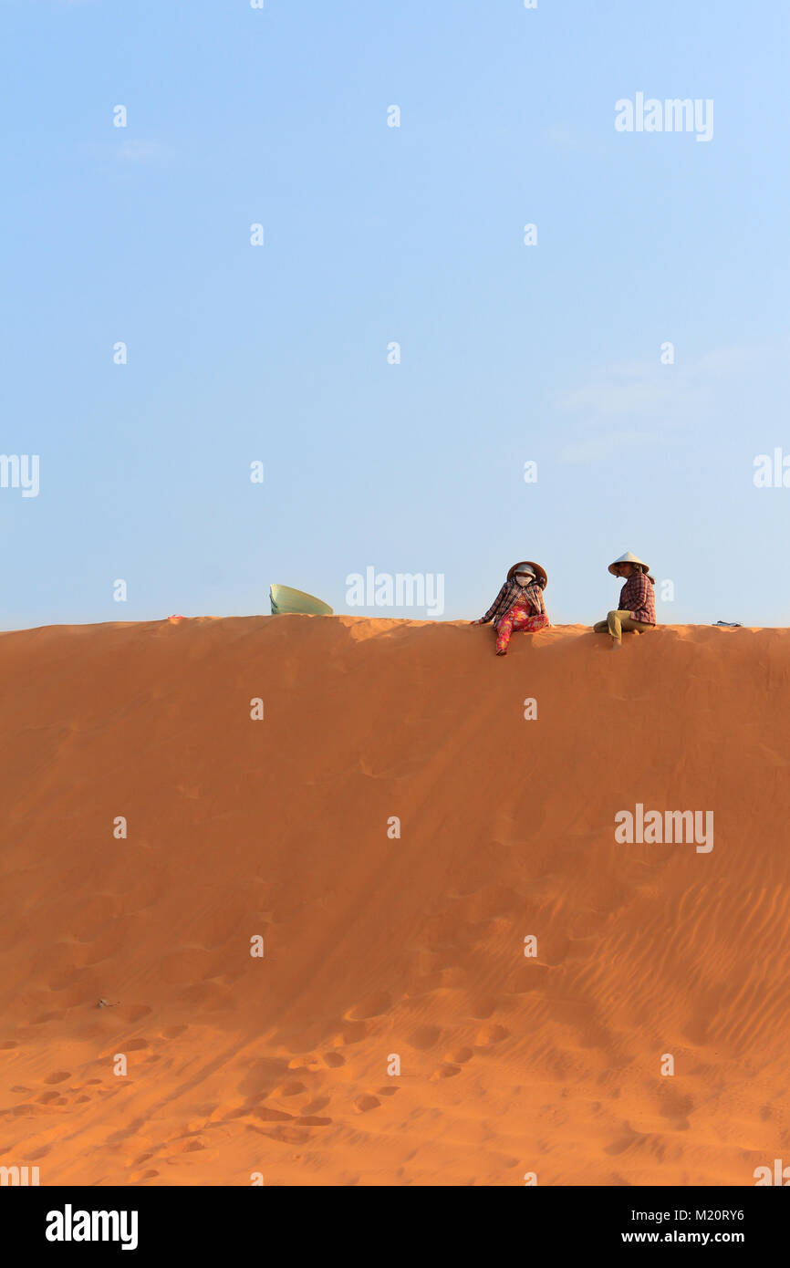 Zwei vietnamesische Frauen auf rotem Sand Dune in Mui Ne Vietnam sitzen Stockfoto