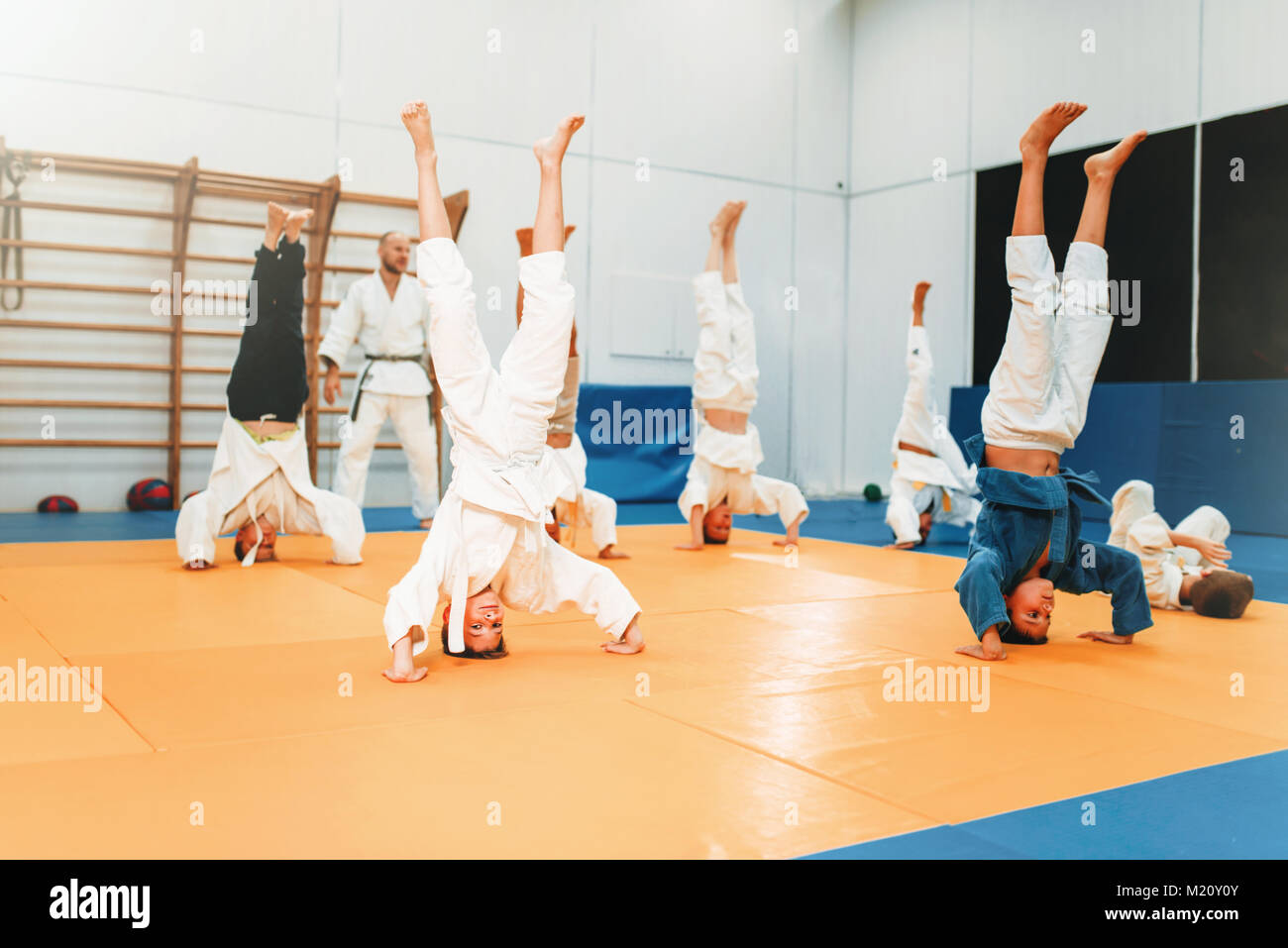 Kinder Karate, Kinder im Kimono Praxis Kampfkunst in Halle. Kleine Jungen und Mädchen in Uniform auf den sport training, kopfüber Übung Stockfoto