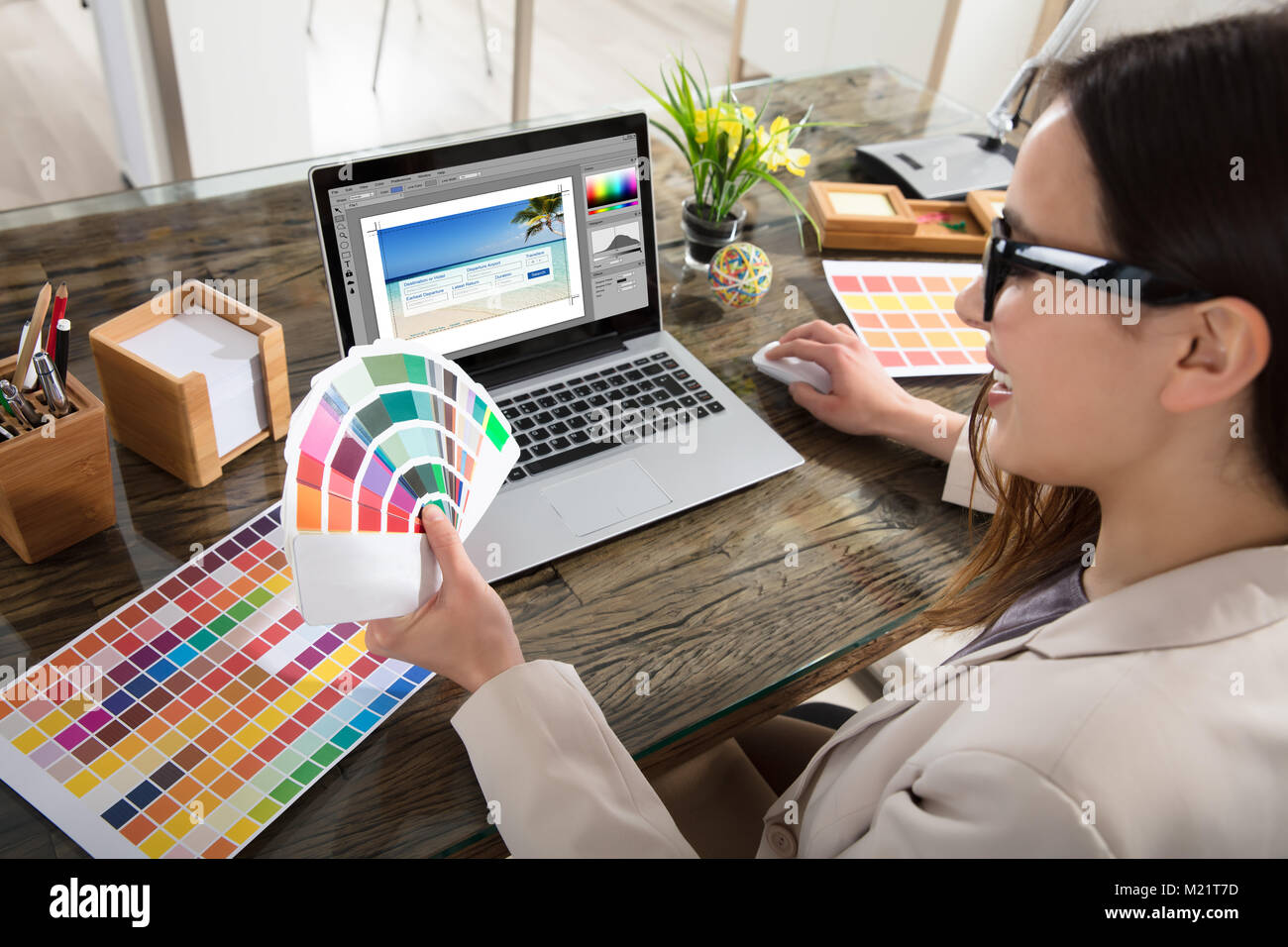 Eine weibliche Designer mit Laptop, während Sie Farbe in Ihre Hand Muster Stockfoto