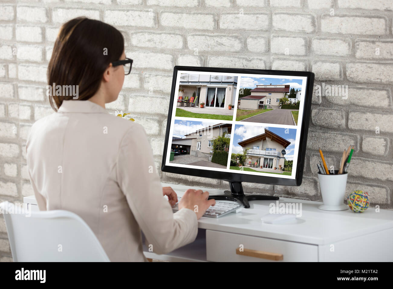 Ansicht der Rückseite eine Geschäftsfrau auf Haus Bilder auf dem Computer im Büro Stockfoto