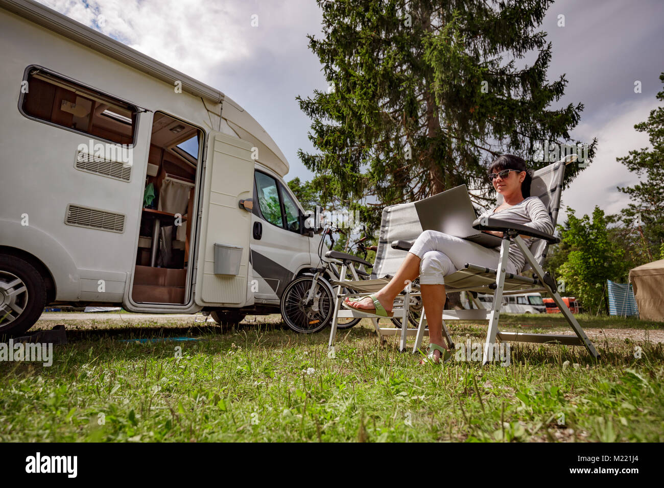 Frau auf dem Laptop in der Nähe des Camping. Caravan Auto Urlaub. Familie Urlaub Reisen, Urlaub im Reisemobil RV. Wi-fi Verbindung Informatio Stockfoto Frau auf dem Laptop in der Nähe des Camping. Caravan Auto Urlaub. Familie Urlaub Reisen, Urlaub im Reisemobil RV. Wi-fi Verbindung Informatio Stockfoto